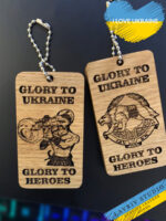 This Ukrainian  wooden keychain is an expression of true artistry and national pride. Crafted from natural wood, it features an exquisite illustration embodying the glory and bravery of the Ukrainian people. Depicting a historical Ukrainian warrior with modern weaponry, the keychain symbolizes the aspiration for victory in the ongoing war on our homeland, Ukraine. On the back side of our Ukrainian wooden keychain you will find an image of a brave wolf, or a coat of arms, or an M142. Please indicate which image you would like when ordering.